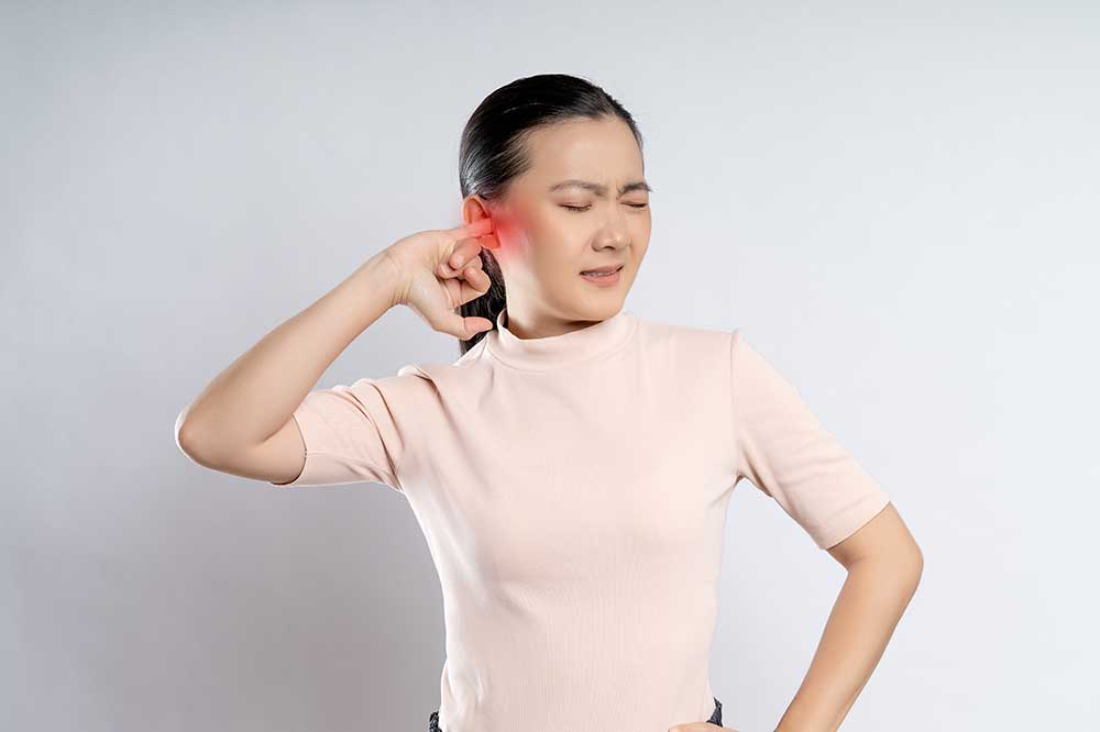 Young woman wincing as she presses a finger into her sore, clogged ear, a concern Port Elgin Audiology sees in Port Elgin, ON